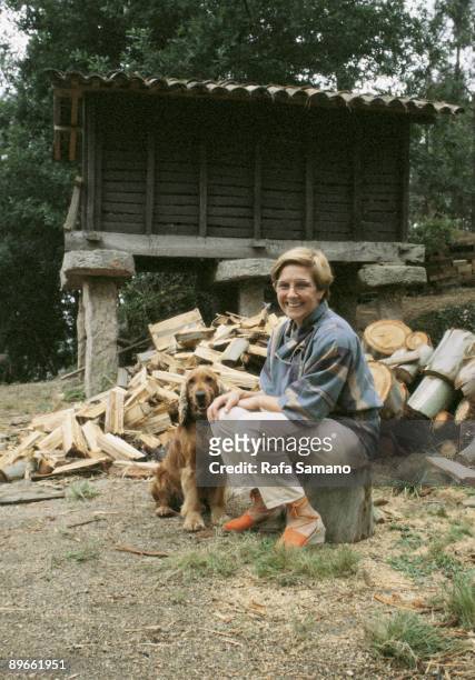 Lola Herrera, actress Lola Herrera in Porrino , sitting in a log next to her dog and a firewood heap
