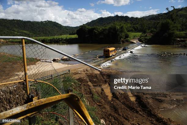 School bus crosses a makeshift bridge for vehicles, near where the original bridge was washed away by Hurricane Maria flooding, on December 20, 2017...