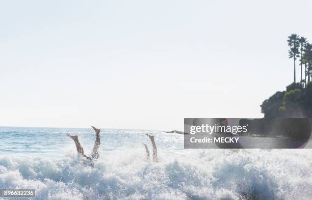 couple fooling around in ocean, flipping over waves - protruding ストックフォトと画像