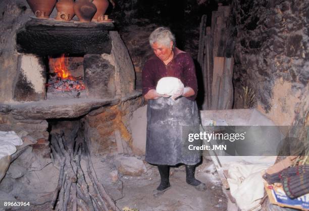 Woman making bread A woman will put a loaf of bread in the oven of her house . Moveros de Aliste . Zamora province