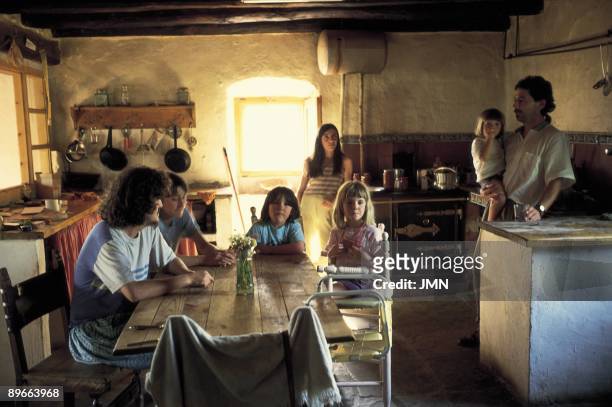Family in the kitchen of a house View of a family in the kitchen of their house in Aineto, abandoned town that has been recovered for young . Huesca...