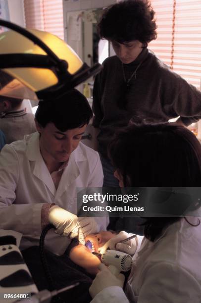 Infantile dentists Two infantile dentists fixing the mouth of a boy in their office