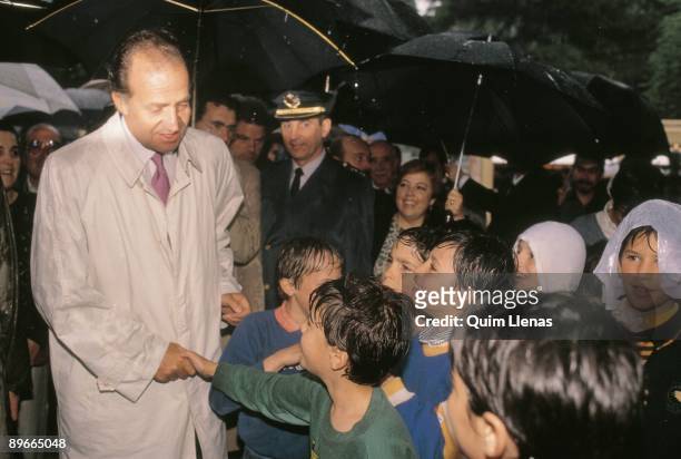 Juan Carlos I inaugurates the Fair of the Book of Madrid The king greets a group of children under the rain