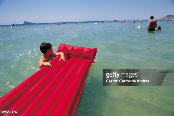 Levante Beach. Benidorm. Alicante A boy with a mattress of water taking a bath in one of the most popular beaches in the tourist mega-city