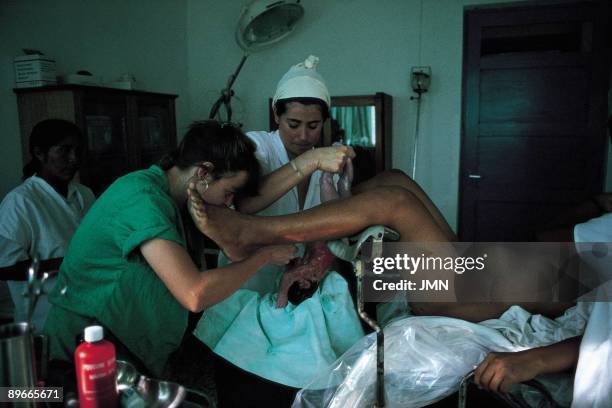 Woman giving birth to in a surgery theater A woman gives birth to helped by a doctor and two nurses in the surgery theater of the Hospital of Doctors...