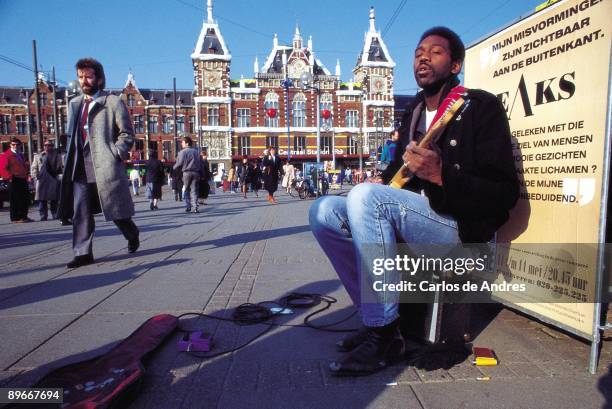 Street musician in Amsterdam A street musician plays the electric guitar in the square of the Central Station of Amsterdam