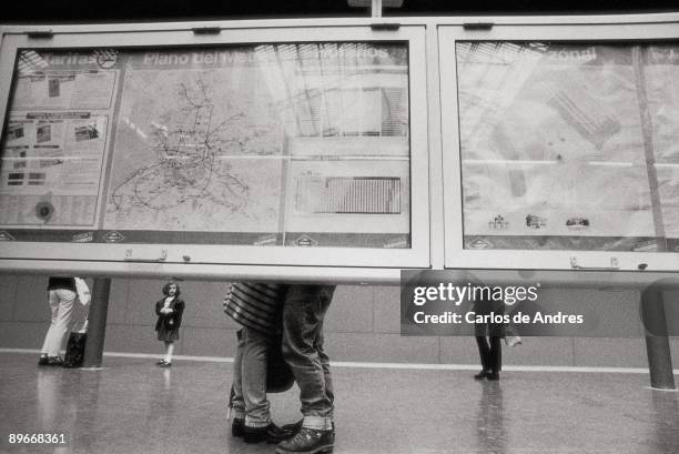 Couple kissing one another in the underground View of a couple being kissin one another behind an informative panel in the platform of a underground...