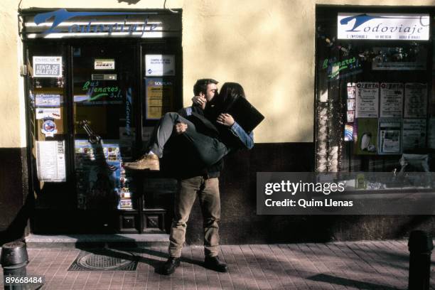 On arms Young man taking a young woman on arms and kissing her at the entrance into a travel agency