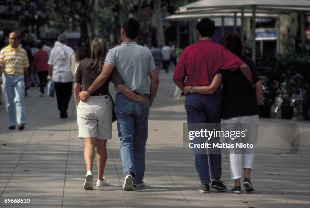 Romantics couples Two couples of youth hugging each other going for a walk in Las Ramblas avenue, Barcelona