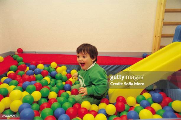 Infantile schoolll A child plays in a pool of balls in a nursery