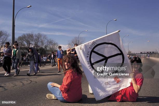 Two seated youngs with the flag of the symbol of the peace. Two seated young woman carry a flag with the symbol of the peace during the march to...