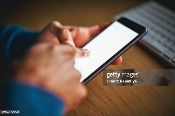male hands tap mobile phone screen, keyboard in background - corporate crime stock pictures, royalty-free photos & images