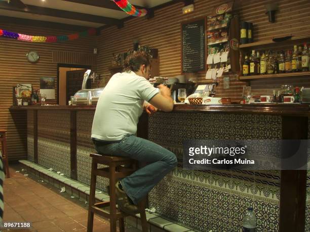 Man drinking a coffee sitting in the bar of a bar.