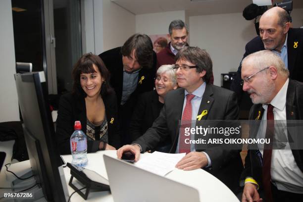 Axed Catalan president Carles Puigdemont flanked by deposed government's members looks on a computer at the results of the Catalonia's regional...