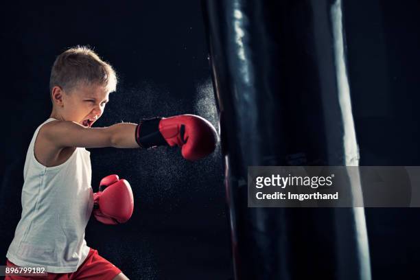petit boxe de formation garçon avec sac de boxe - combative sport stock photos et images de collection