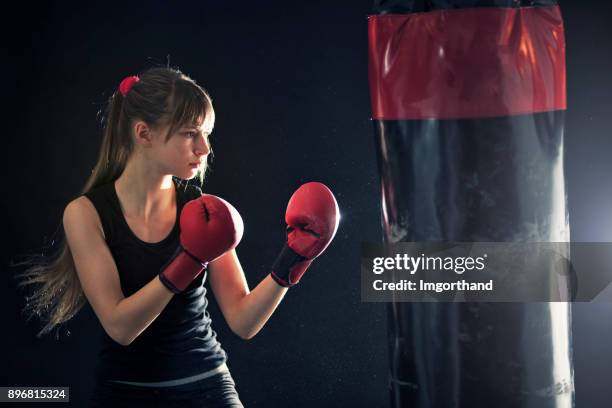 tienermeisje opleiding boksen met bokszak - kids boxing stockfoto's en -beelden