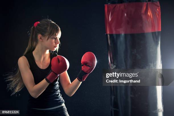 teenage girl training boxing with punching bag - kid boxing stock pictures, royalty-free photos & images