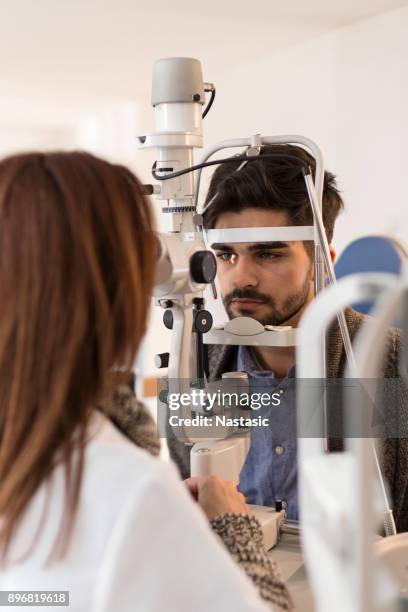 young man having his eyes examined - eye test equipment stock pictures, royalty-free photos & images