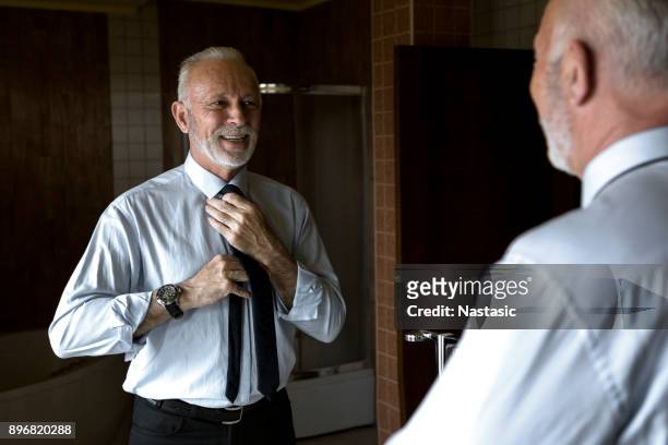 mature man looking in mirror - neckwear stock pictures, royalty-free photos & images