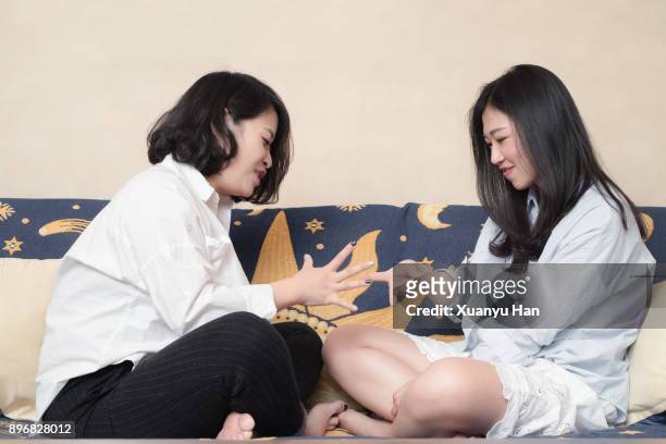 young loving female couple relaxing on sofa in the living room and communicating. - lesbian - rock paper scissors stock pictures, royalty-free photos & images