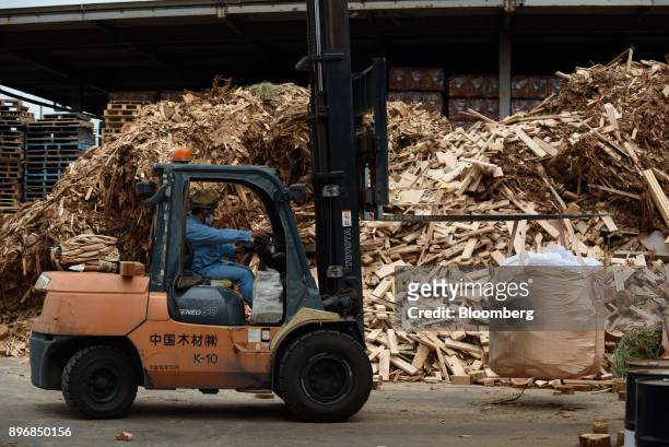 Worker drives a forklift past piles of scrap wood at the Gonoike Biomass Power Station, operated by Gonoike Bioenergy Corp., a subsidiary of...