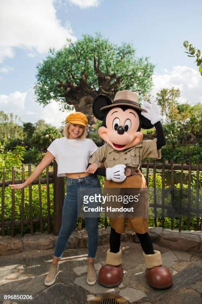 In this handout photo provided by Disney Parks, Hollywood Records artist and actress Olivia Holt poses with Mickey Mouse at Disney's Animal Kingdom...