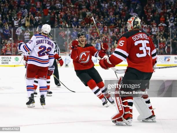 Steven Santini and Cory Schneider of the New Jersey Devils celebrate their 4-3 shootout victory over the New York Rangers at the Prudential Center on...