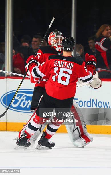 Cory Schneider of the New Jersey Devils is congratulated by Steven Santini after defeating the New York Rangers in a shootout at Prudential Center on...