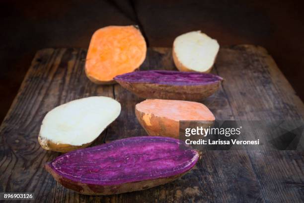 different sweet potatoes on dark wood, cut in half - larissa veronesi - fotografias e filmes do acervo