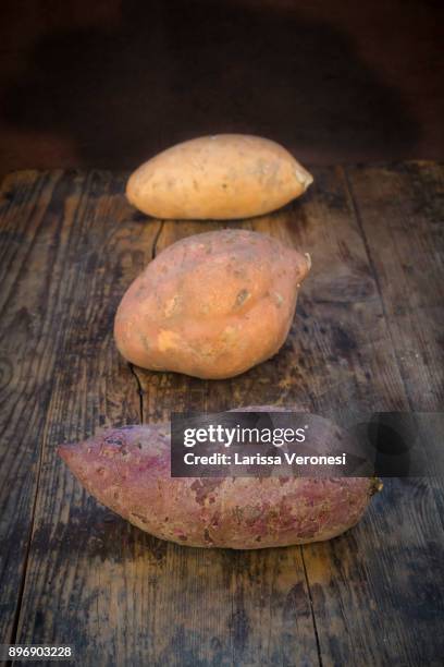 different sweet potatoes on dark wood - larissa veronesi stockfoto's en -beelden