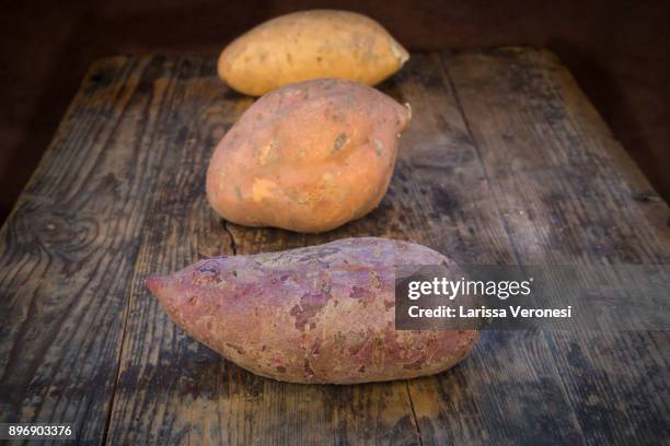 different sweet potatoes on dark wood - larissa veronesi - fotografias e filmes do acervo