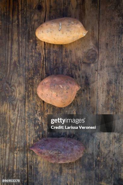 different sweet potatoes on dark wood - larissa veronesi stockfoto's en -beelden