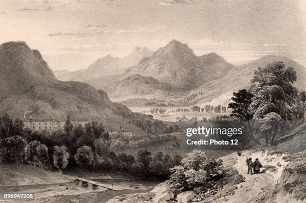 The Inn at Capel Curig from Moel Siabod' near Betws-y-Coed, Snowdonia, North Wales. In the left foreground a simple wooden plank bridge spans the...