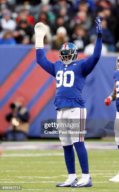 Jason Pierre-Paul of the New York Giants, with his right arm bandaged, raises his arms to get the fans cheering in an NFL football game against the...
