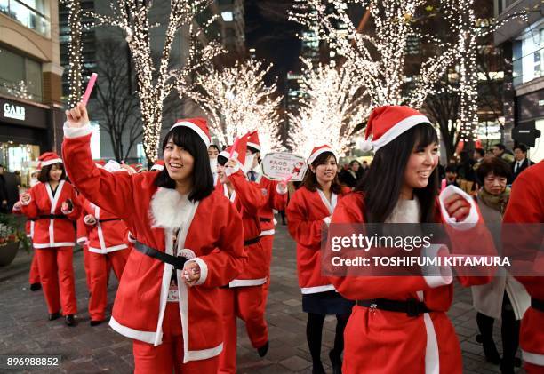 Marunouchi shop clerks and workers wearing Santa Claus costumes join a Christmas parade at the Marunouchi shopping district in Tokyo on December 22,...