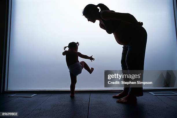 silhouette of pregnant mother with dancing daughter - dancer kicking silhouette stock pictures, royalty-free photos & images