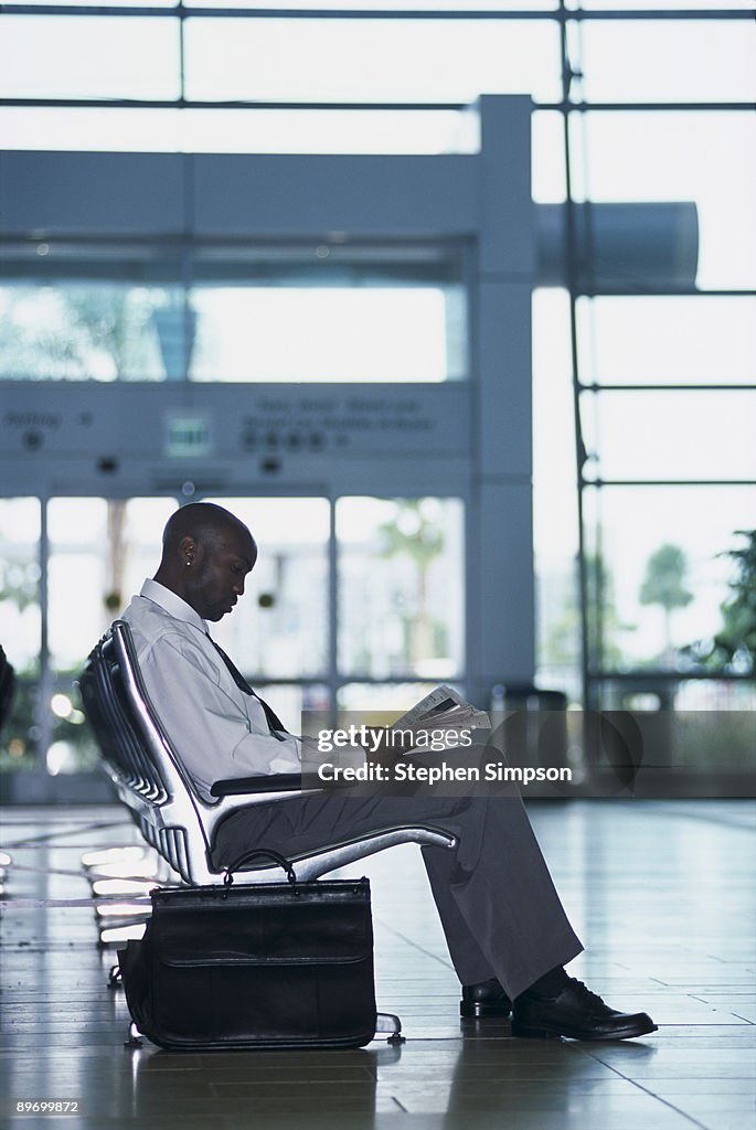 Businessman reading magazine in airport terminal