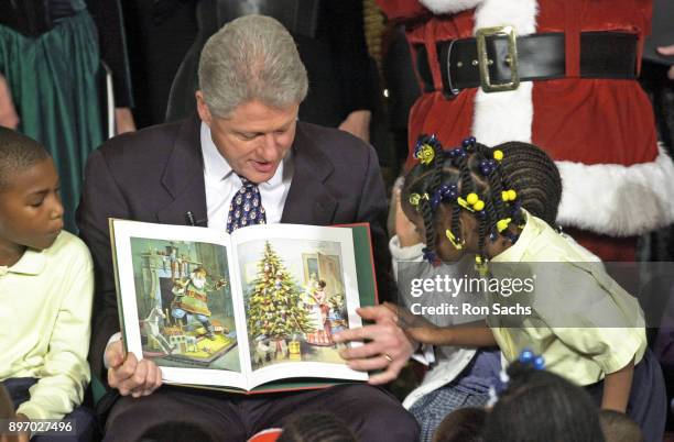 American politician US President Bill Clinton reads ''Twas The Night Before Christmas' to a group of elementary school children at the White House,...