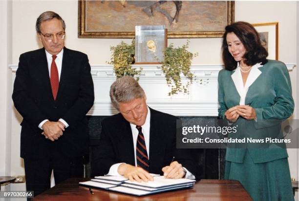 Senate Majority Leader George Mitchell and US Representative Nancy Pelosi watch as American politician US President Bill Clinton signs an executive...