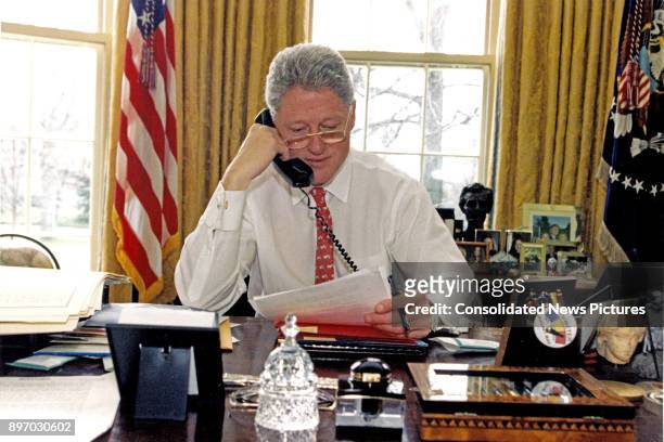 American politician US President Bill Clinton speaks on the telephone in the White House's Oval Office, Washington DC, February 27, 1997. He was...