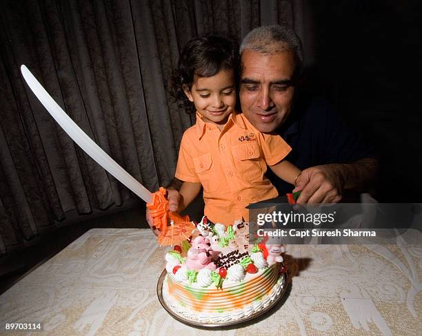 young boy cutting his birthday cake with toy sword - panchkula stockfoto's en -beelden