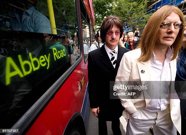 Beatles tribute band walk beside a bus near the zebra crossing used in the photoshoot for the Beatles album Abbey Road outside the Abbey Road Studios...