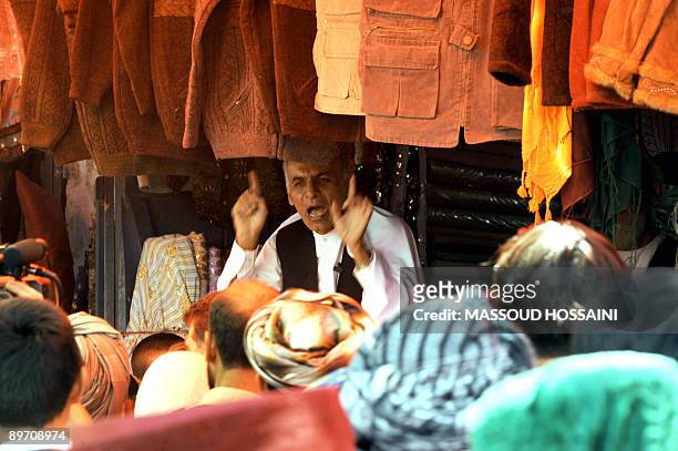 Afghan presidential candidate and former finance minister Ashraf Ghani talks as he campaigns at a market in Maymana city of the northern province...