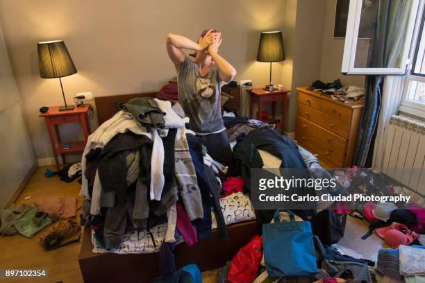 portrait of woman crying among tiles of clothes in a messy bedroom - chaos to order ストックフォトと画像