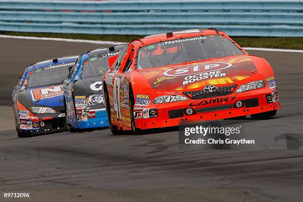 Marcos Ambrose, driver of the STP Toyota, leads Kevin Harvick, driver of the Copart Chevrolet, and Kyle Busch, driver of the NOS Toyota, during the...