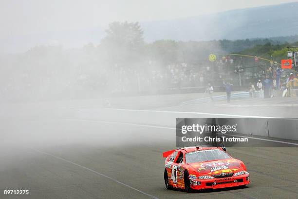 Marcos Ambrose, driver of the STP Toyota, waves the checkered flag on the track from his car after winning the NASCAR Nationwide Series Zippo 200 at...
