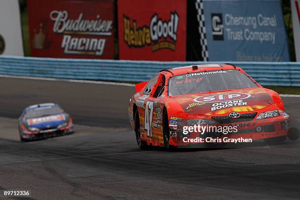 Marcos Ambrose, driver of the STP Toyota, leads Kyle Busch, driver of the NOS Toyota on the last lap in the NASCAR Nationwide Series Zippo 200 at...