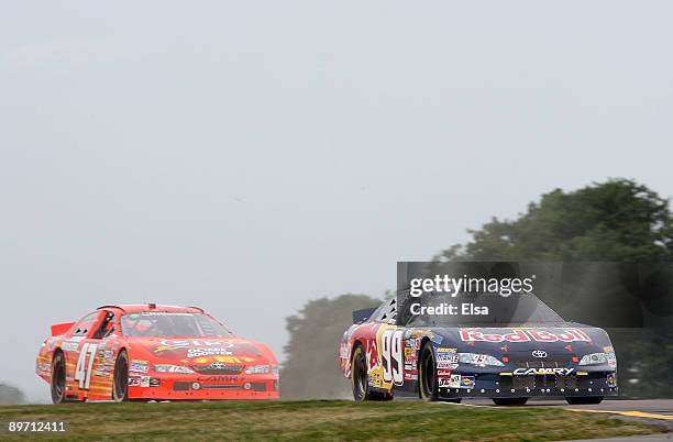 Scott Speed, driver of the Red Bull Toyota, leads Marcos Ambrose, driver of the STP Toyota, during the NASCAR Nationwide Series Zippo 200 at Watkins...