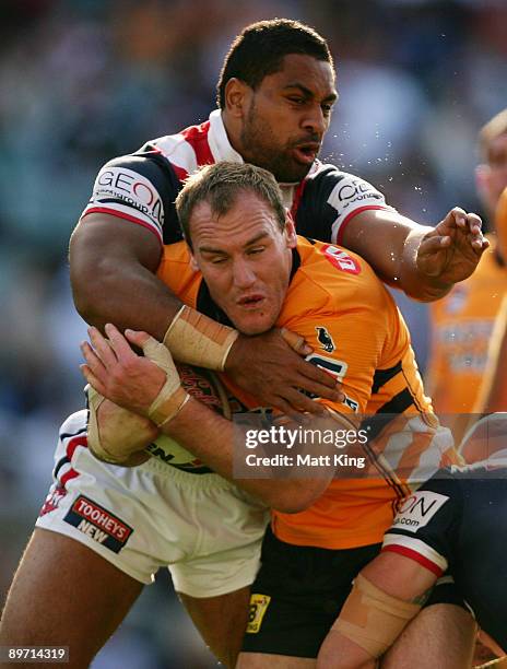 Gareth Ellis of the Tigers is tackled by Lopini Paea of the Roosters during the round 22 NRL match between the Sydney Roosters and the Wests Tigers...