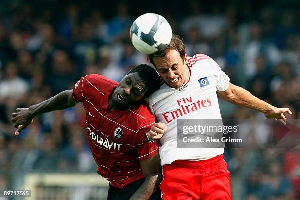 Mohamadou Idrissou of Freiburg jumps for a header with Joris Mathijsen of Hamburg during the Bundesliga match between SC Freiburg and Hamburger SV at...